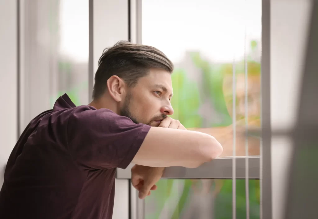 contemplative man looking out the window utc