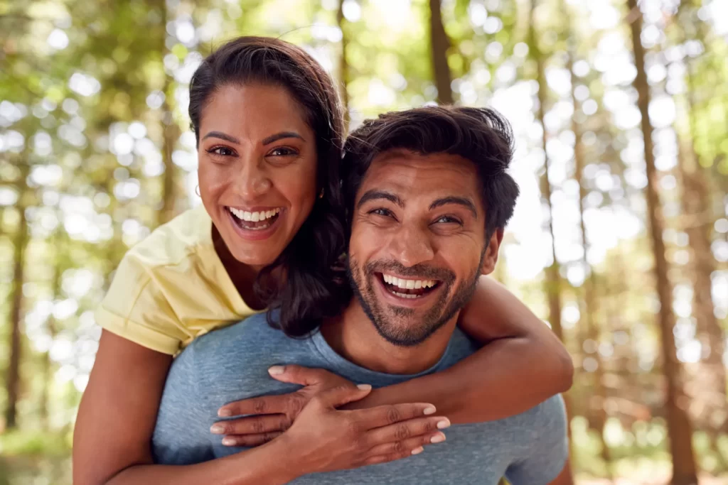 smiling couple embrace in the woods together utc
